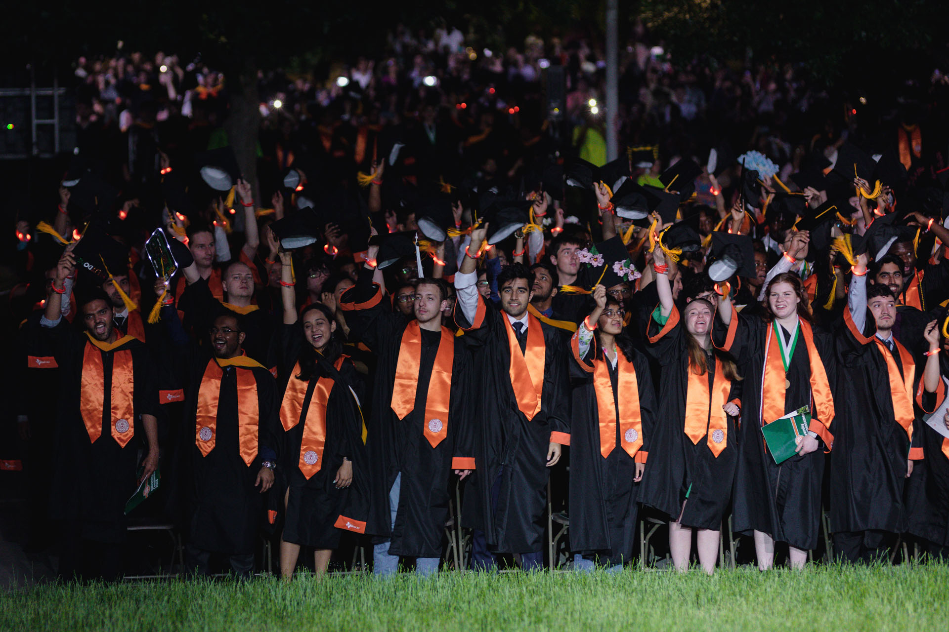 Graduates raise their mortarboards and perform the Comet Wave.