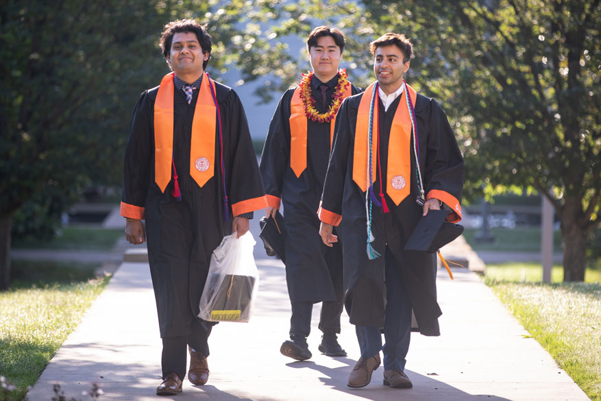 New graduates walk past magnolia trees on campus